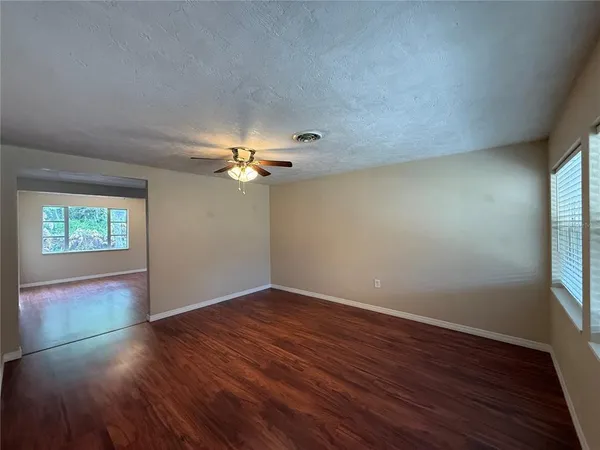 a view of empty room with wooden floor and fan