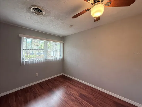 an empty room with a wooden floor and windows