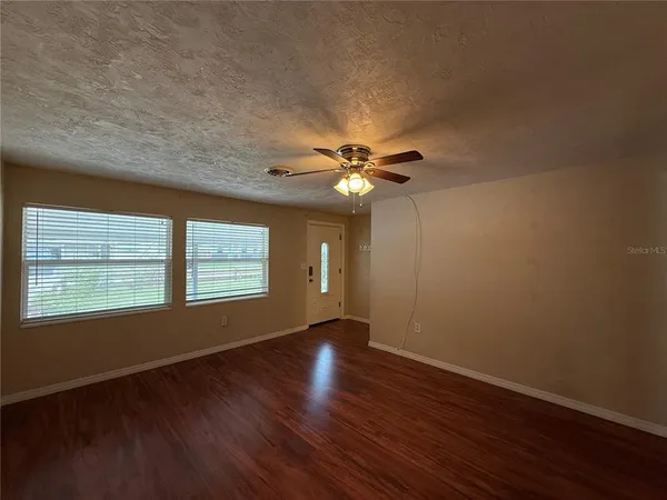 a view of an empty room with wooden floor and a window