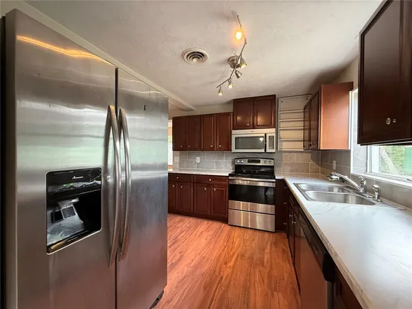 a kitchen with stainless steel appliances granite countertop a refrigerator a stove a sink and a microwave