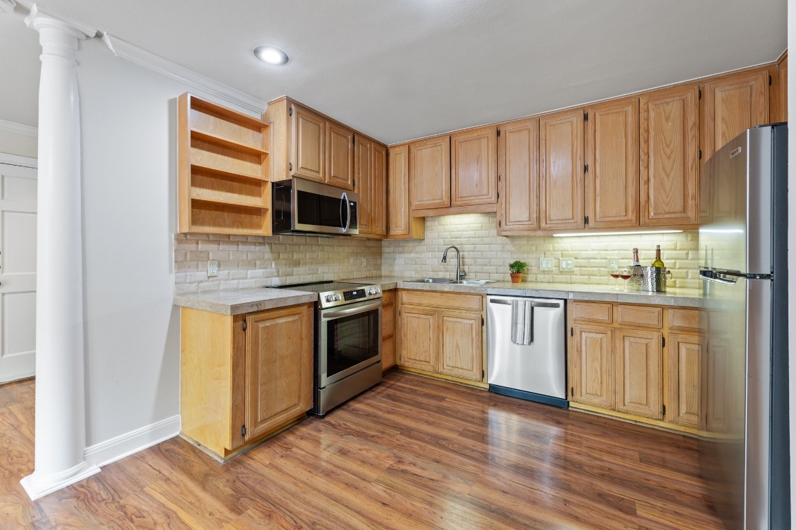 a kitchen with granite countertop a sink cabinets stainless steel appliances and wooden floor