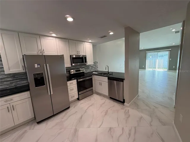 a kitchen with stainless steel appliances granite countertop a stove a sink and a refrigerator