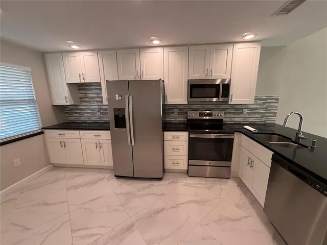 a kitchen with stainless steel appliances a refrigerator and a stove top oven