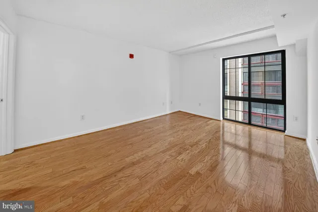 a view of an empty room with wooden floor and a window