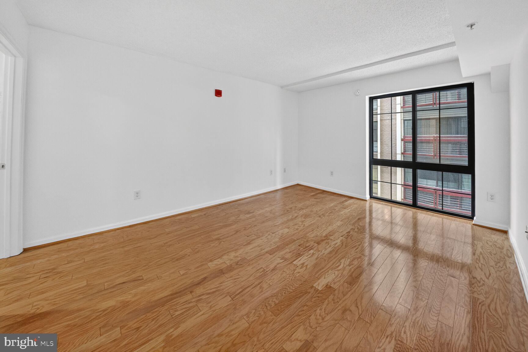 7923 Eastern Avenue Northwest, Unit 404 Silver Spring, MD 20910 - Photo 9 of 20 a view of an empty room with wooden floor and a window