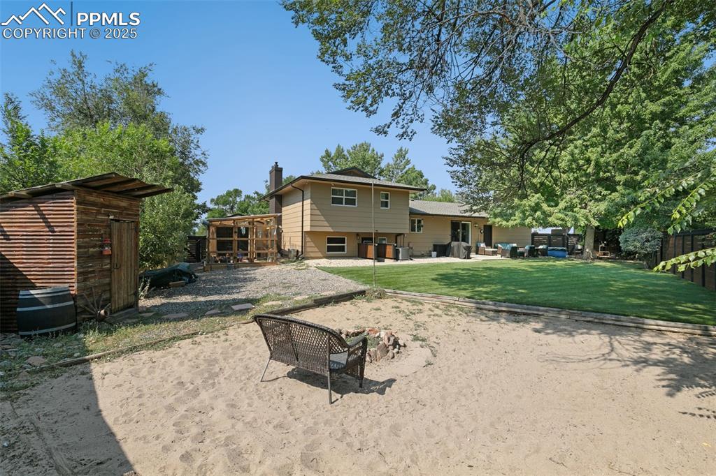 1921 Van Diest Road Colorado Springs, CO 80915 - Photo 44 of 45 Rear view of house with a patio, a chimney, a storage shed, and a lawn