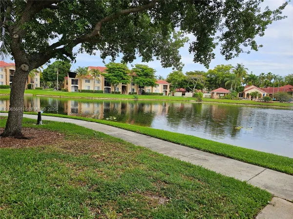 a view of a lake with a yard and large trees