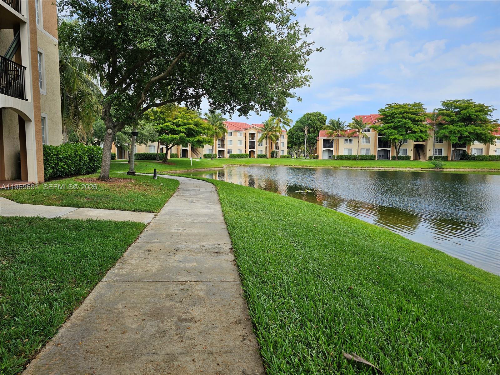 2051 Renaissance Boulevard, Unit 104 Miramar, FL 33025 - Photo 38 of 39 a view of a lake with a yard and large trees