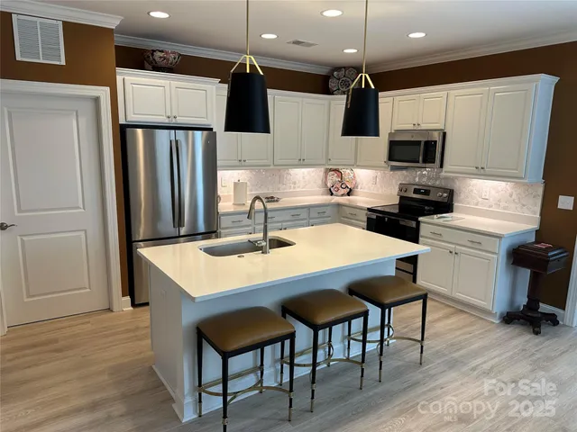 a kitchen with stainless steel appliances granite countertop a sink a stove a refrigerator and island with wooden floor
