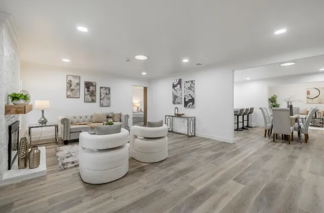 a living room with lots of white furniture and a wooden floor