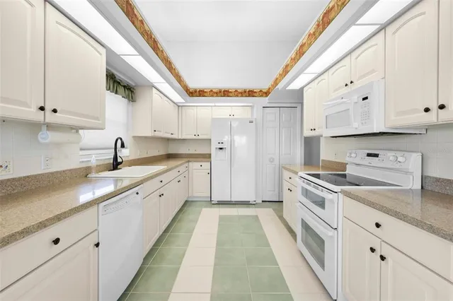 a kitchen with granite countertop white cabinets and a sink