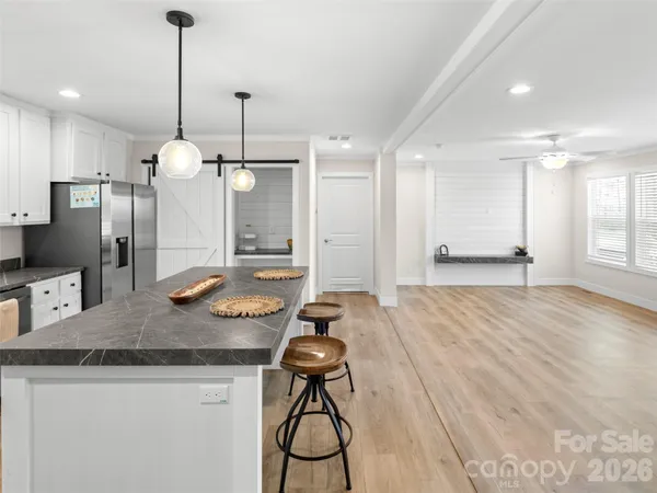 a open kitchen with stainless steel appliances granite countertop a stove top oven a sink dishwasher and a refrigerator with wooden floor