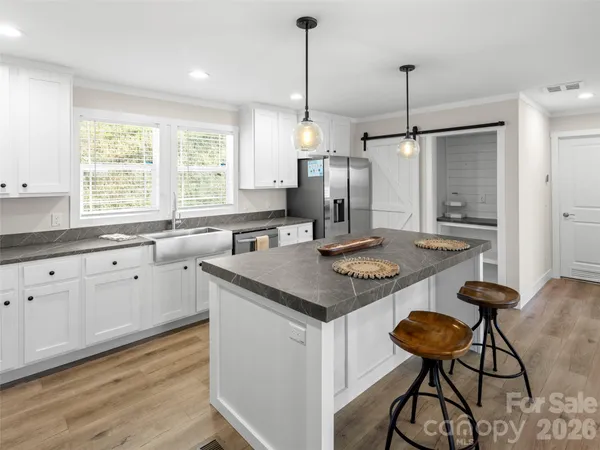 a kitchen with stainless steel appliances granite countertop a stove top oven a chimney cabinets and wooden floor