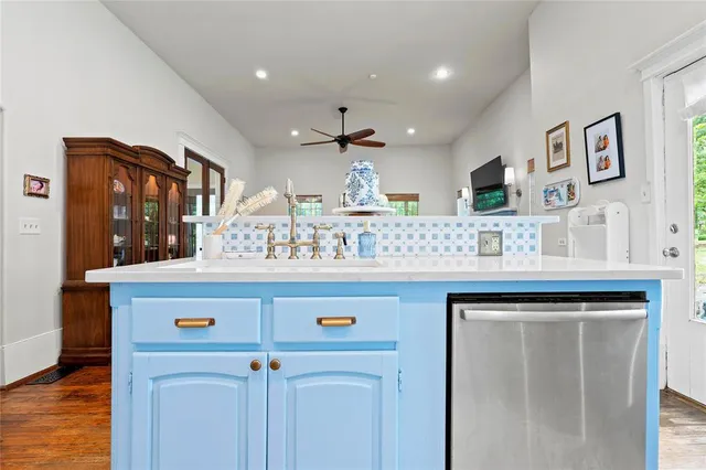 a view of kitchen with kitchen island stainless steel appliances a sink and wooden floor