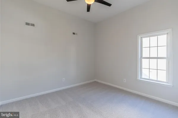 an empty room with chandelier fan and windows