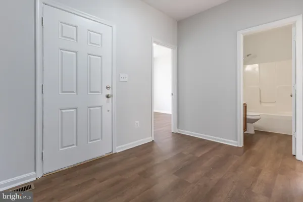 an empty room with wooden floor and a bathroom