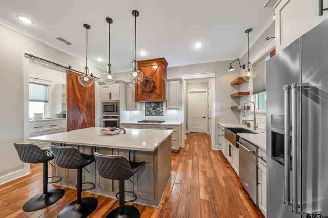 a kitchen with granite countertop a table chairs stainless steel appliances and cabinets