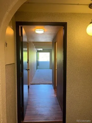 a view of a hallway with wooden floor and a living room