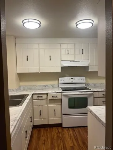 a kitchen with cabinets stainless steel appliances and a wooden floor