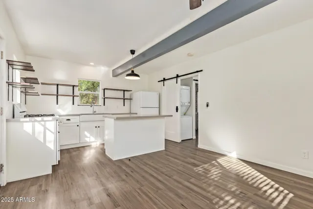 a kitchen with stainless steel appliances wooden floors and white walls
