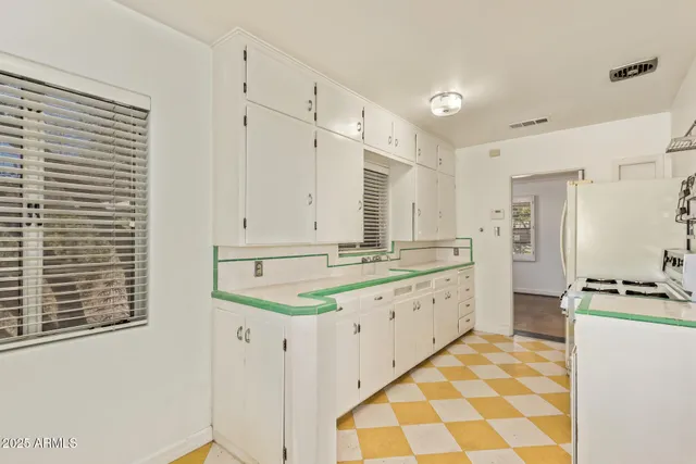 a large white kitchen with a stove a sink a refrigerator and cabinets