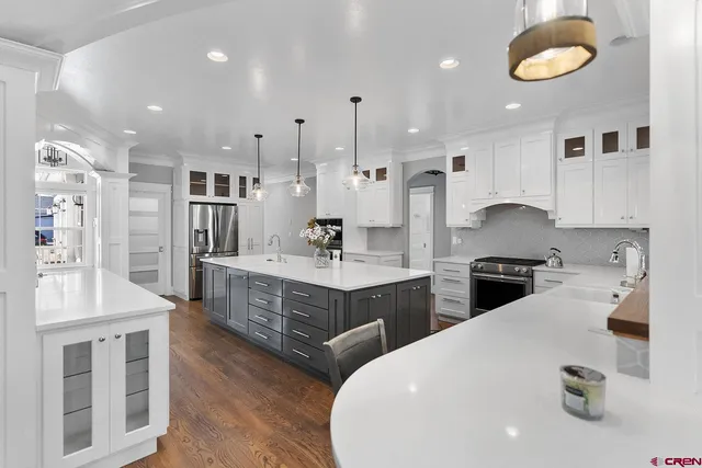 a kitchen with stainless steel appliances a sink a stove a refrigerator cabinets and living room view