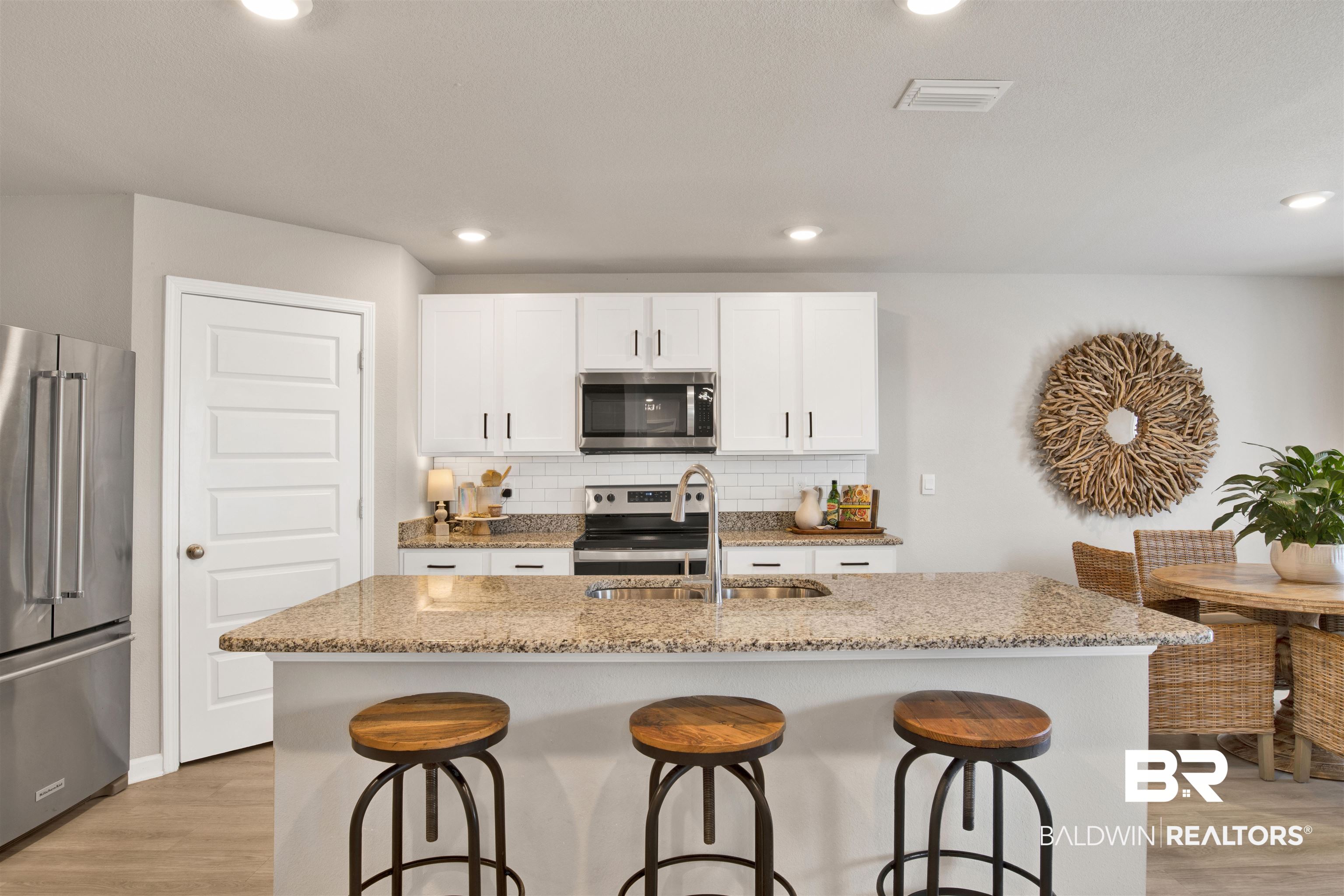 24532 Broken Sound Loop Orange Beach, AL 36561 - Photo 10 of 29 Kitchen with backsplash, stainless steel appliances, light hardwood / wood-style flooring, and a center island with sink