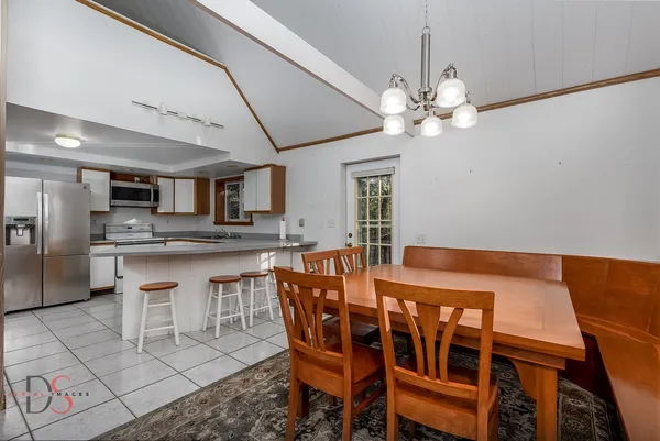 a dining room with stainless steel appliances kitchen island granite countertop a table chairs and a refrigerator