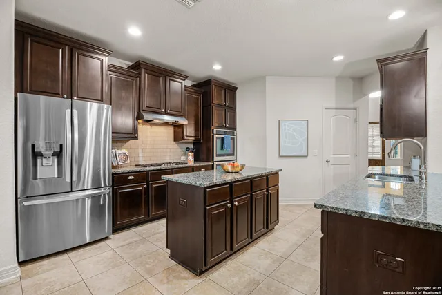 a kitchen with stainless steel appliances granite countertop a stove refrigerator and cabinets