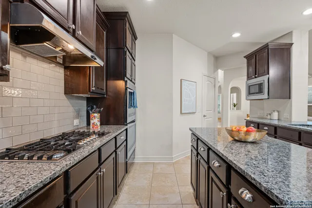 a kitchen with stainless steel appliances granite countertop a sink stove and cabinets
