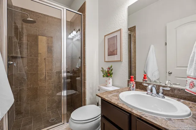 a bathroom with a granite countertop sink a toilet a mirror and shower