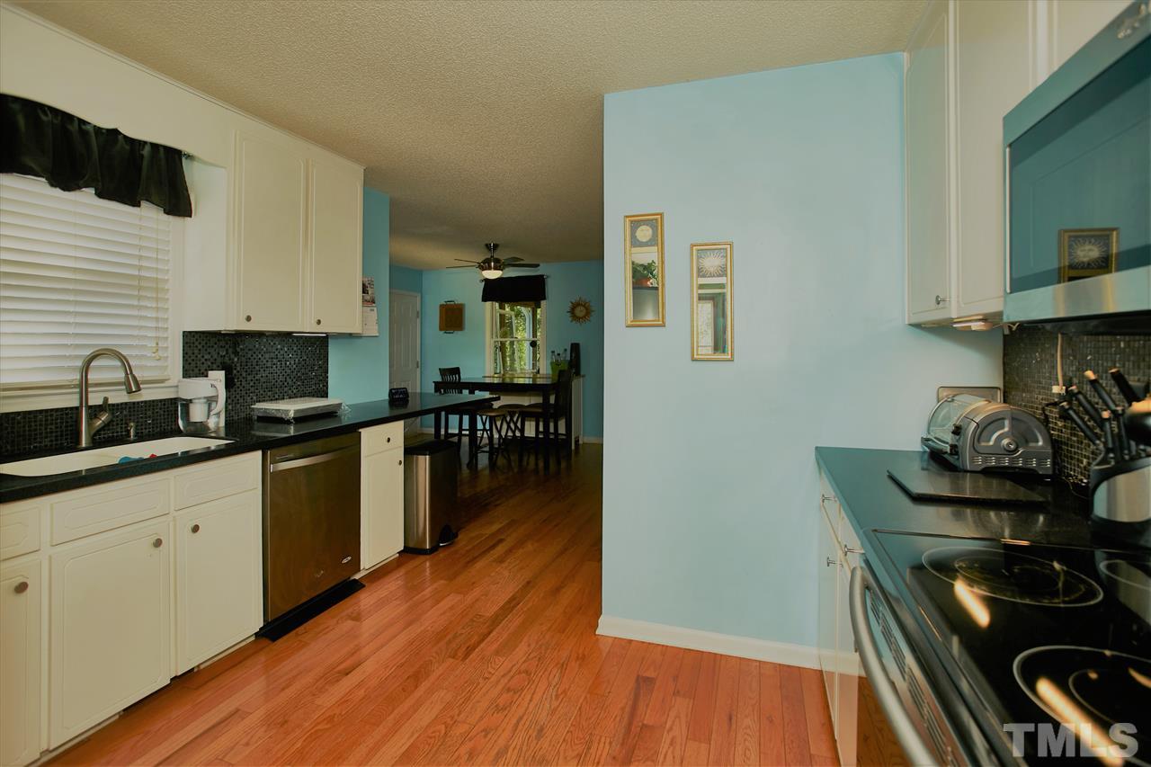 517 Jordan Ridge Lane Raleigh, NC 27603 - Photo 6 of 16 a kitchen with granite countertop wooden floors and stainless steel appliances