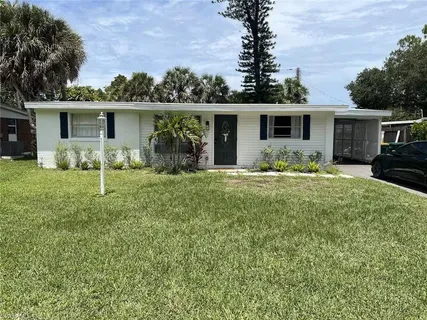 a front view of house with yard and trees in the background