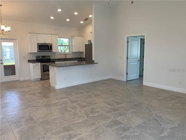 a view of kitchen with kitchen island granite countertop stainless steel appliances stove top oven and cabinets