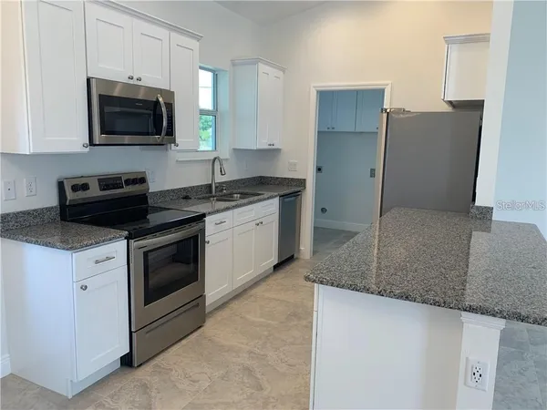 a kitchen with stainless steel appliances granite countertop a stove a sink and a microwave