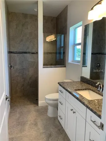 a bathroom with a granite countertop sink toilet and shower
