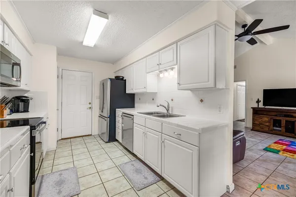 a kitchen with white cabinets a sink a stove and a refrigerator