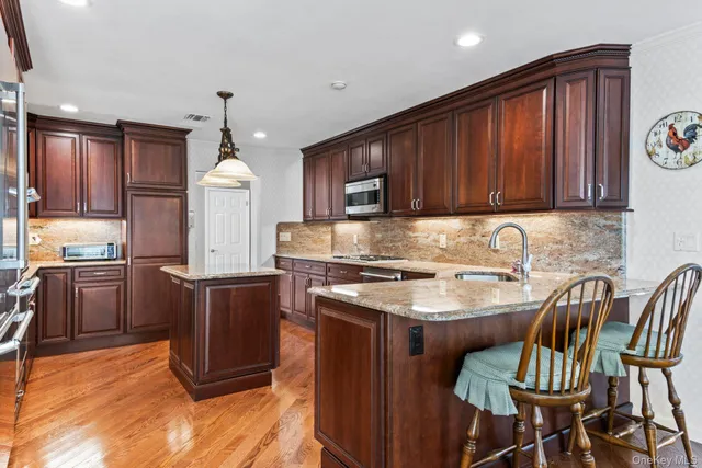 a kitchen with granite countertop wooden cabinets a stove a oven a dining table and chairs