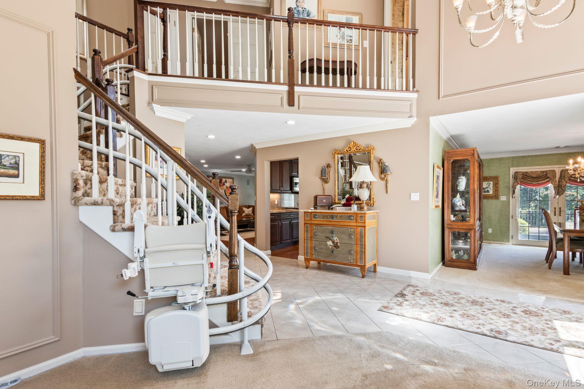 77 The Woods Commack, NY 11725 - Photo 6 of 31 Foyer entrance with a high ceiling, a chandelier, ornamental molding, light tile patterned flooring, and stairs