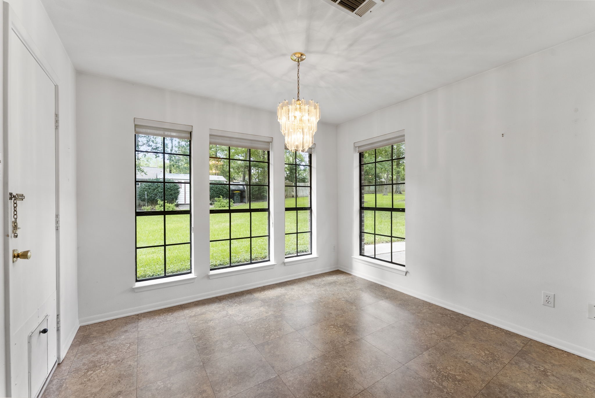 202 Sunset Boulevard Conroe, TX 77303 - Photo 23 of 50 This inviting breakfast area boasts abundant natural light from expansive windows overlooking a lush garden, enhanced by a stylish chandelier for a perfect morning retreat.