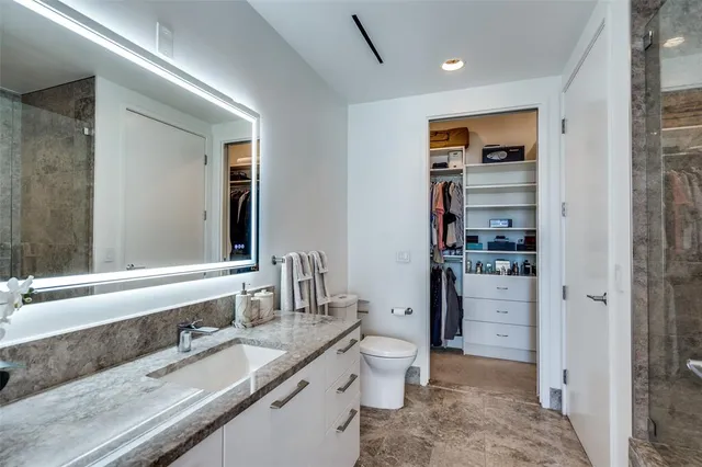 a bathroom with a granite countertop sink mirror vanity and toilet