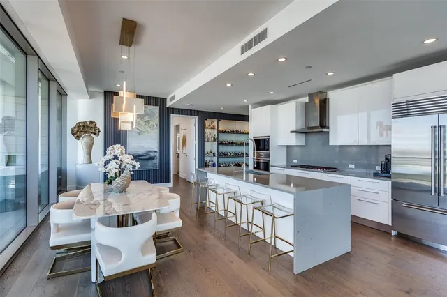 a kitchen with stainless steel appliances kitchen island granite countertop a table chairs sink and cabinets
