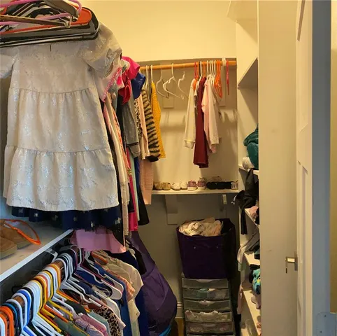 a view of walk in closet with clothes and shoes