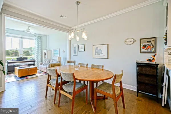 a dining room with wooden floor a chandelier a wooden table and chairs