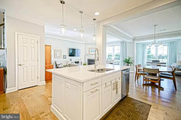 a open kitchen with kitchen island a stove a sink dishwasher and white cabinets with wooden floor