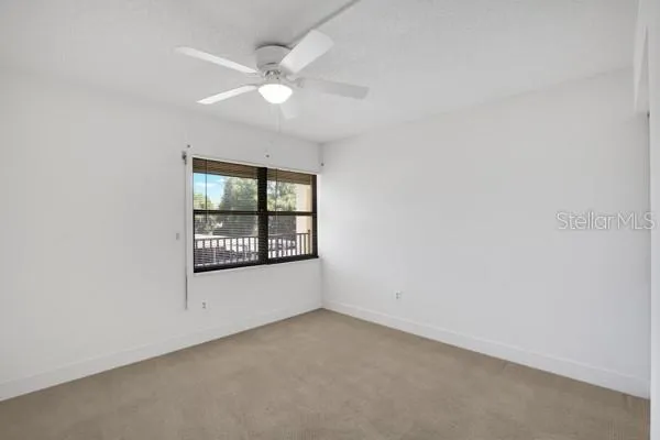 an empty room with windows and fan