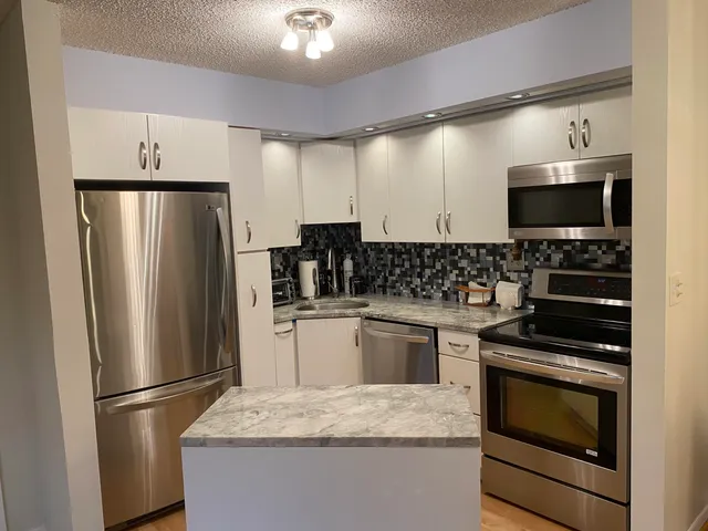 a kitchen with stainless steel appliances granite countertop a refrigerator stove and sink
