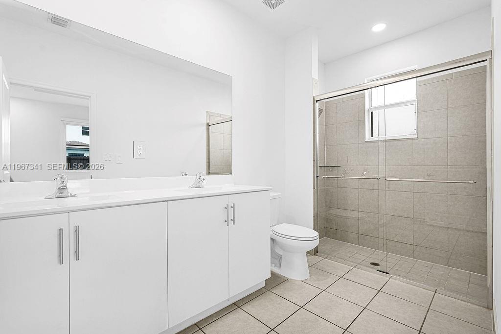 12735 Southwest 211th Street Miami, FL 33177 - Photo 21 of 34 a bathroom with a double vanity sink a toilet and a mirror