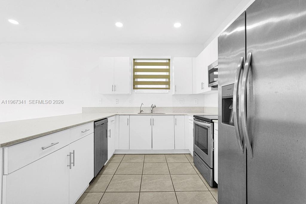12735 Southwest 211th Street Miami, FL 33177 - Photo 4 of 34 a kitchen with white cabinets stainless steel appliances and a sink