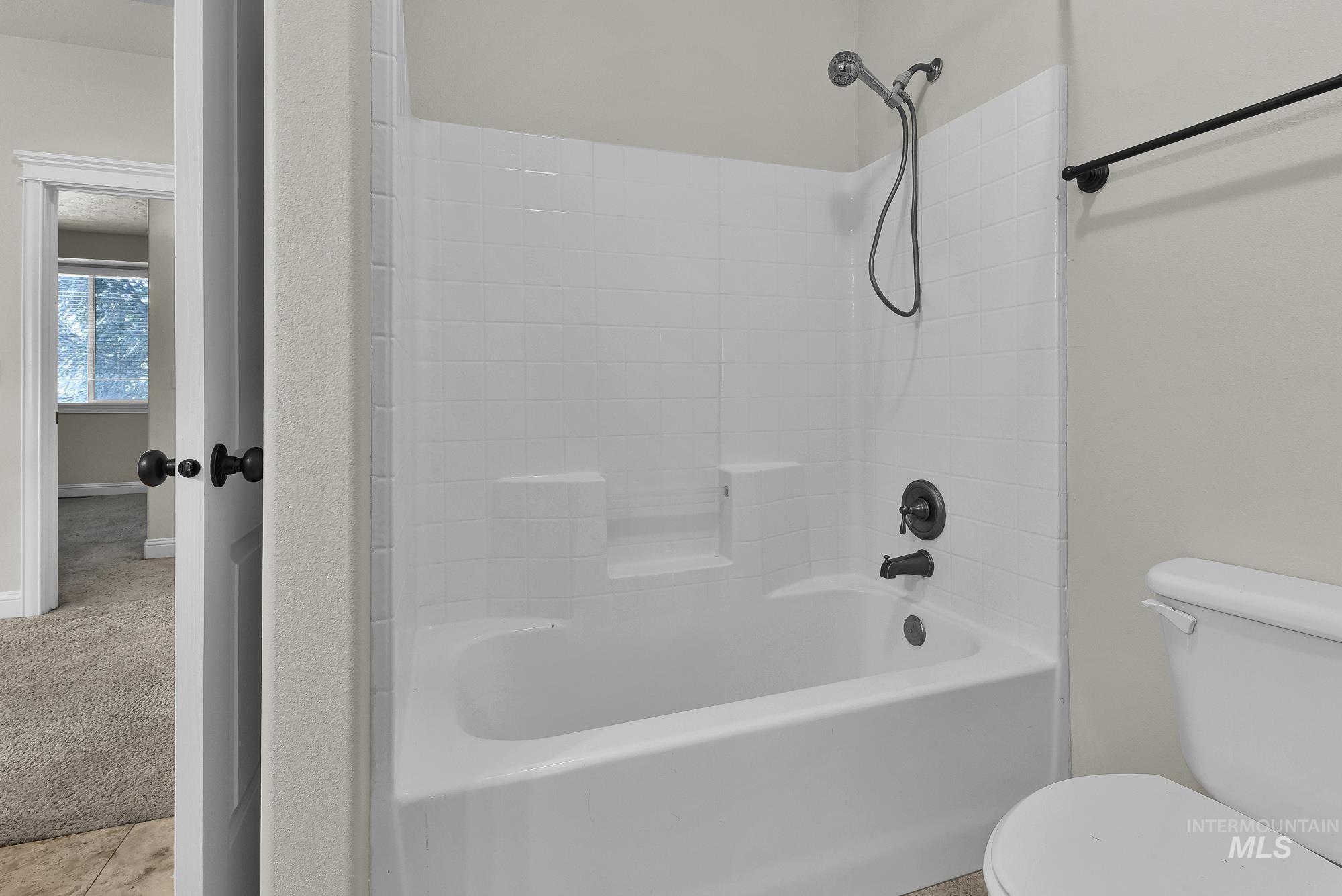 2172 West Cedar Grove Street Meridian, ID 83646 - Photo 31 of 49 Bathtub and shower combination featuring a white tile surround and dark bronze fixtures